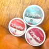 Kingston nicotine pouches in different nicotine strengths and a variety of flavours on wood background