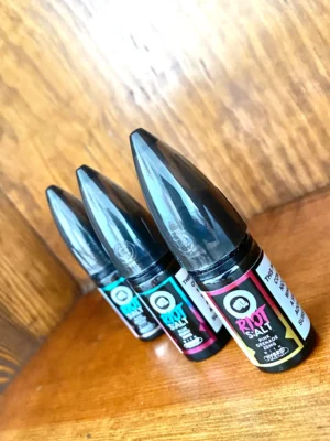 Riot-squad-nicotine-salt-10ml Riot squad nicotine salts 10ml in 10mg and 20mg strengths and a variety of flavours on wood background