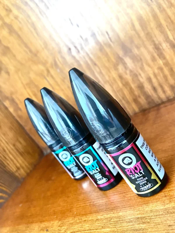 Riot squad nicotine salts 10ml in 10mg and 20mg strengths and a variety of flavours on wood background