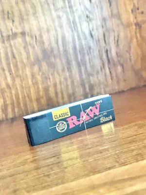 Raw classic black rolling paper tips on wood background